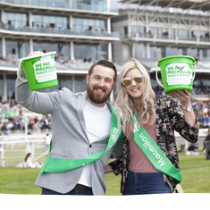 Supporters smiling with green buckets at Macmillan Charity Raceday in York.